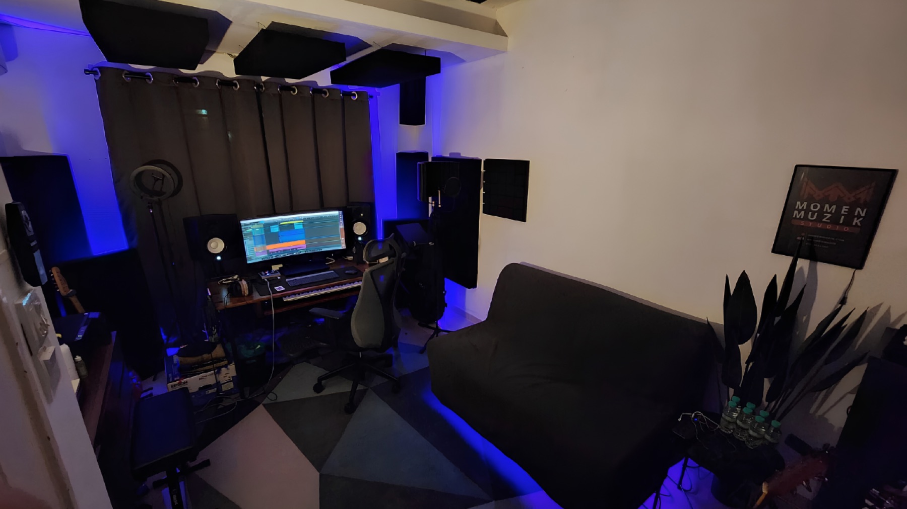 Inside Momen Muzik Studio: recording desk, microphone and a sofa in the blue-lit room